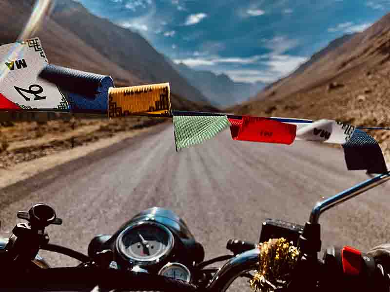 A Motorcycle on a road trip to Spiti I Buddhist prayer flags on a Bike on its Journey to the mystical Himalayan Tour, 2023